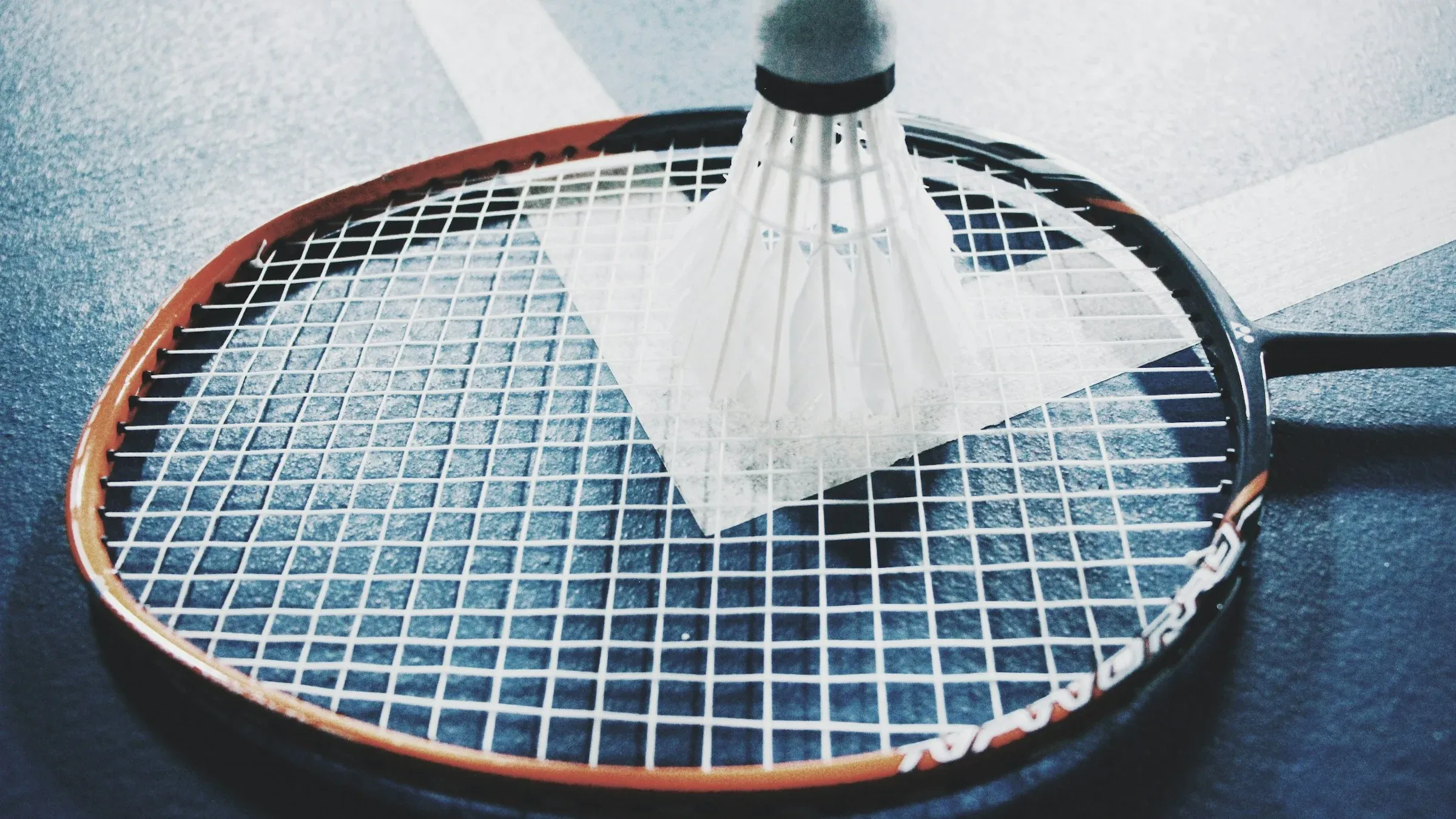 Volant de badminton posé sur une raquette au sol